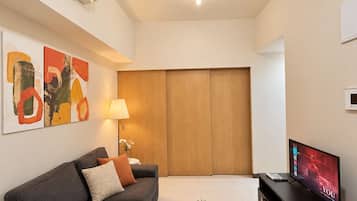A modern living room with a grey sofa, a coffee table, a TV, and an air conditioning unit mounted on the wall.