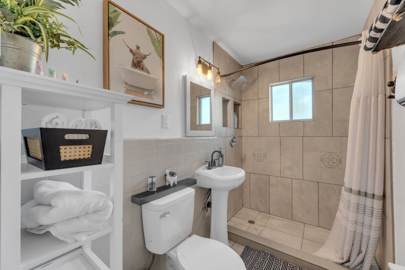 Une salle de bain moderne équipée de toilettes, d’un lavabo, d’une douche et d’une étagère où sont rangées les serviettes.