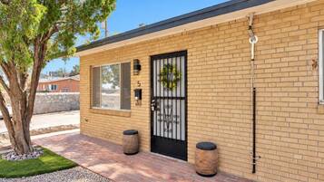 A brick building with a black metal gate, a small tree, and two cylindrical planters.