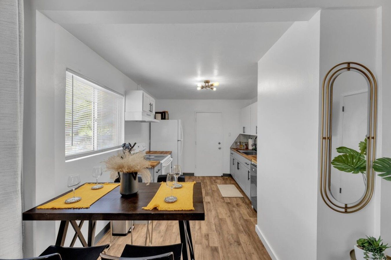 A modern kitchen with white cabinets, a wooden countertop, and a dining area with a table set for two.