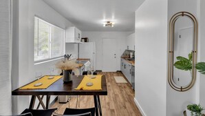 A modern kitchen with white cabinets, a wooden countertop, and a dining area with a table set for two. - Central 2BR | Workspace, Laundry & Long Stays (El Paso)