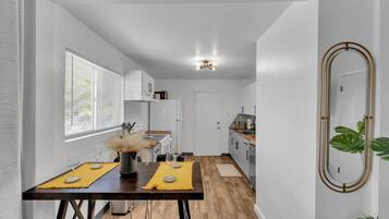 A modern kitchen with white cabinets, a wooden countertop, and a dining area with a table set for two.
