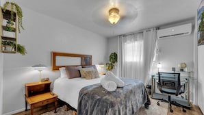 A bedroom with a bed, bedside table, lamp, and a desk with a chair. - Central 2BR | Workspace, Laundry & Long Stays (El Paso)