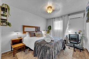 Une chambre à coucher comprenant un lit, une table de chevet, une lampe et un bureau avec une chaise.