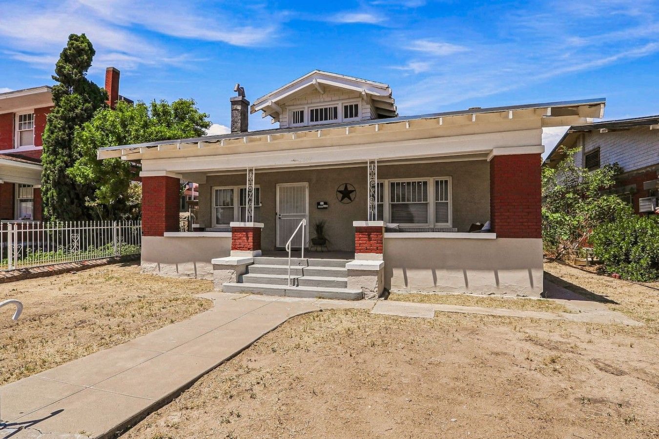 Une maison à deux étages avec un porche à l’avant, un garage et une cour clôturée.