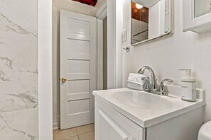 A bathroom with a white sink, a mirror, and a bottle of soap.