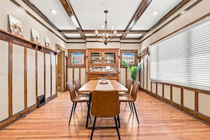 Un comedor con mesa de madera, sillas y una araña.