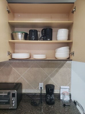 A kitchen with a toaster, coffee maker, and a cabinet with dishes and cookware. - "Courtyard Arms"  family friendly (Toronto)