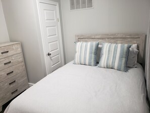 A bedroom with a bed, two pillows, a dresser, and a door. - "Courtyard Arms"  family friendly (Toronto)