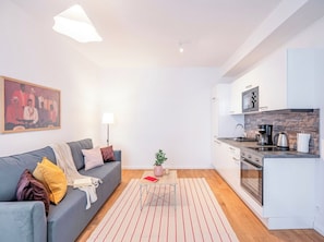 A compact living space with a kitchenette, a sofa with cushions, a small table, and a plant. - Emora | The Artful Prague Retreat (Prague)