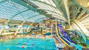 An indoor water park with multiple swimming pools, slides, and a large covered area. - Mod Artist Loft | Near University | 10 min to DT (Edmonton)