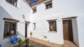 Un patio con un edificio blanco, una silla azul y plantas en macetas.
