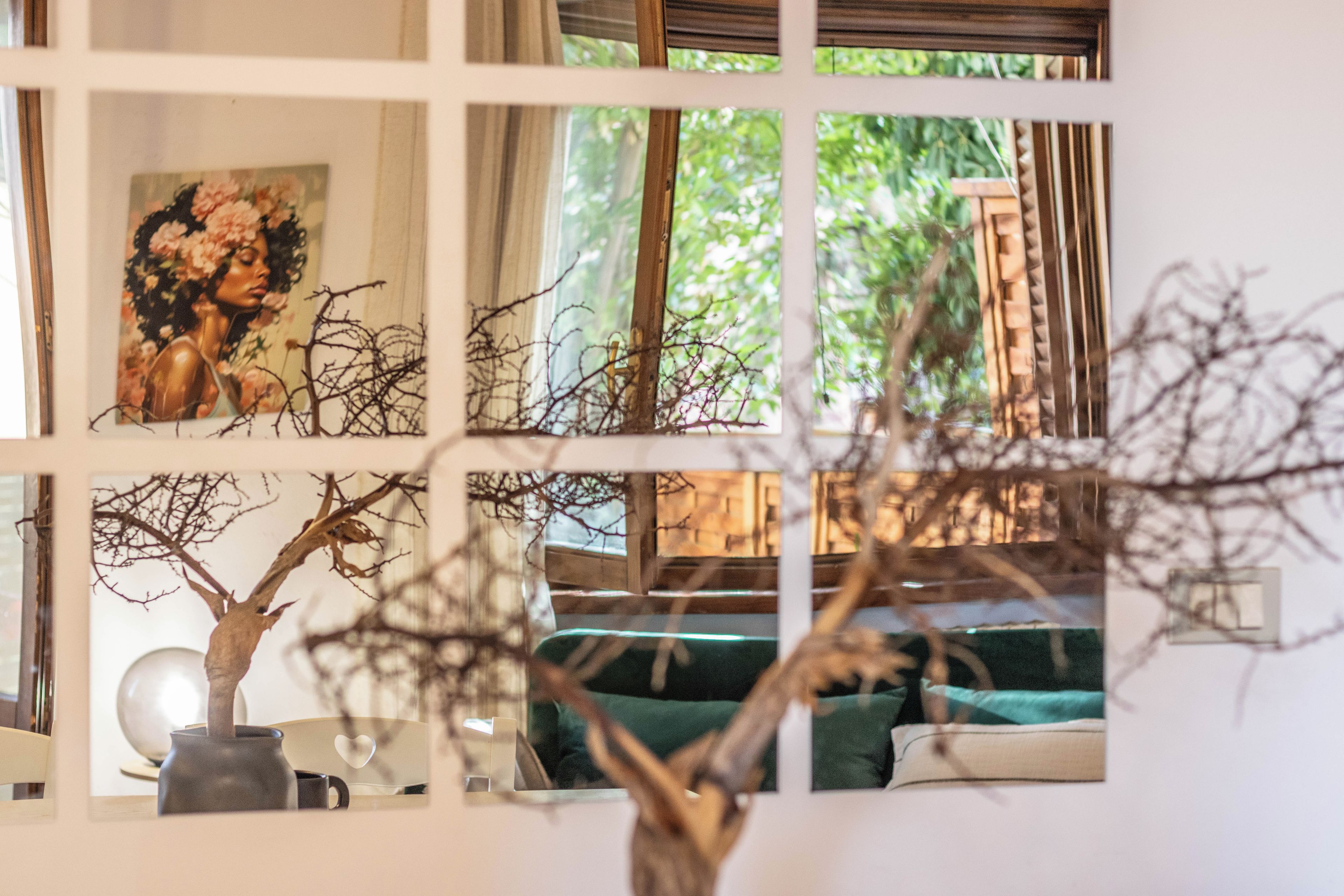 A room with a window, a painting, a vase, and a plant.