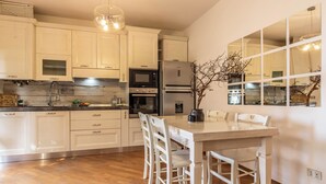 Une cuisine moderne avec des meubles blancs, un îlot central doté de chaises et un grand miroir placé au-dessus de l’îlot.