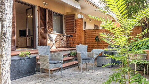 Un espace extérieur aménag é en terrasse, avec des meubles en osier, une table et une chaise.