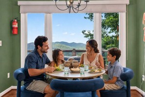 Una familia comiendo en una mesa redonda con vista a las montañas.