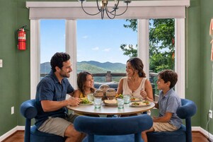 A family dining at a round table with a view of mountains.