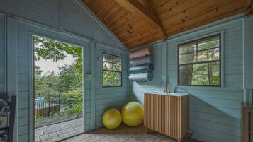 Una habitación con techo de madera, una ventana, un lavamanos y pelotas de ejercicio.