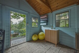 Una habitación con techo de madera, una ventana, un lavamanos y pelotas de ejercicio.