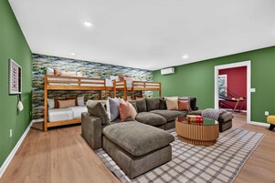 A room with a bunk bed, a sofa, a coffee table, and a patterned rug.