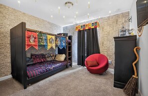 A room with a bed, a red chair, and a wall with banners. - Low-Tox Theme Park Retreat • 2 Private Theaters (Four Corners)