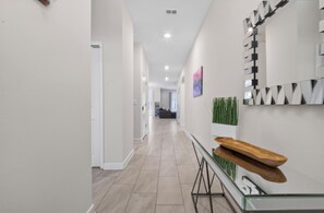 A modern hallway with a glass railing, a wooden tray, and a wall-mounted mirror. - Low-Tox Theme Park Retreat • 2 Private Theaters (Four Corners)