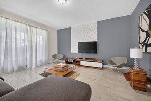 A modern living room with a flat-screen TV, two armchairs, a coffee table, and a bookshelf. - Low-Tox Theme Park Retreat • 2 Private Theaters (Four Corners)