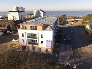 Ein mehrstöckiges Gebäude mit Parkplatz und Meerblick.