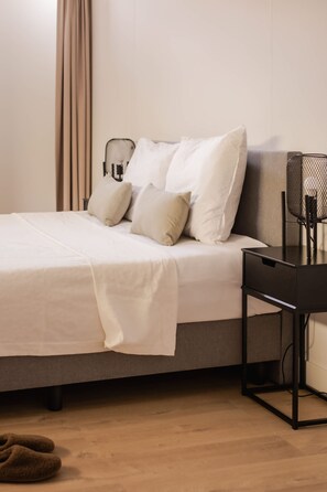 A bed with a white bedspread and multiple pillows, a black desk with a chair, and a wooden floor. - Spacious Duplex in Centre With Free Parking (Rotterdam)