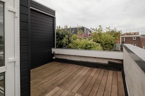 A rooftop terrace with wooden flooring, a black exterior wall, and a white railing. - Grand apt w 2 Private Terraces and Free Parking (Rotterdam)