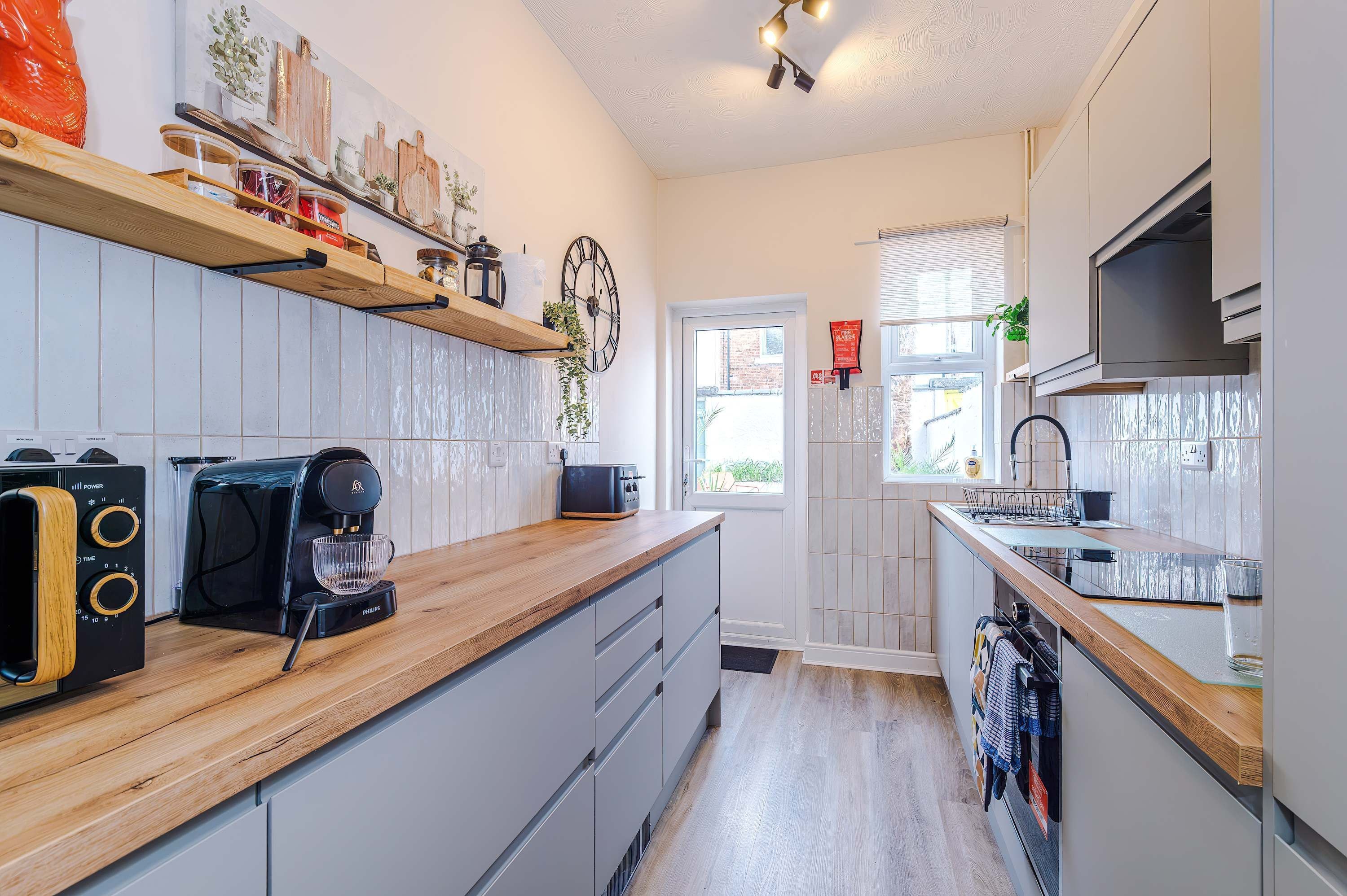 A modern kitchen with a coffee maker, toaster, and wooden shelves.