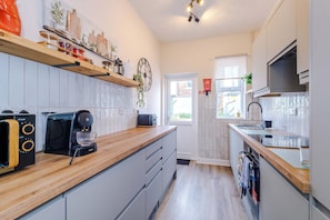 Een moderne keuken met een koffiezetapparaat, broodrooster en houten planken.