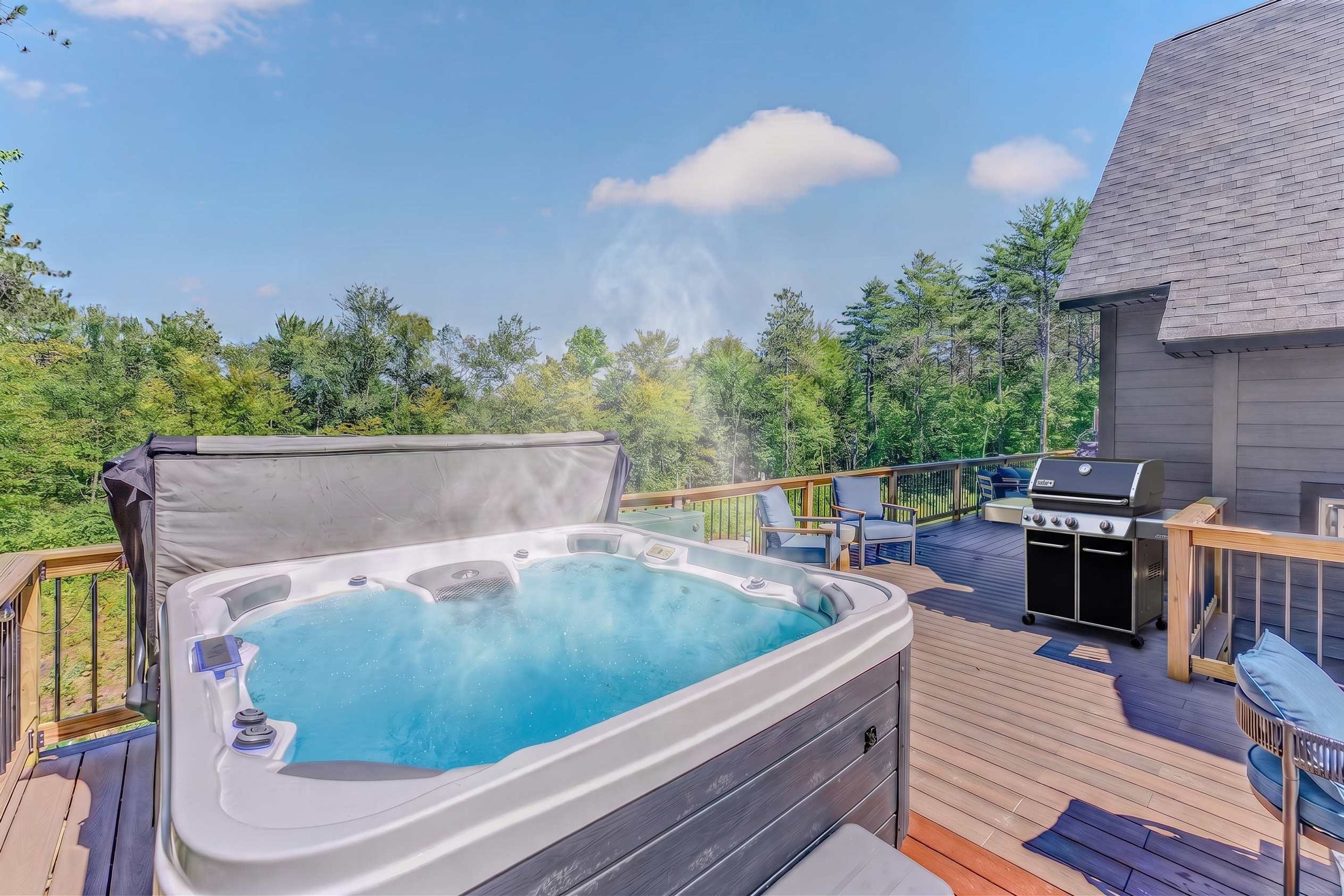A hot tub on an outdoor deck with a grill and seating area.