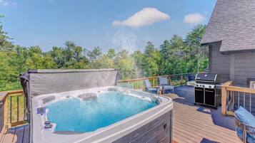 A hot tub on an outdoor deck with a grill and seating area.