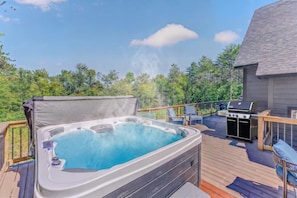 A hot tub on an outdoor deck with a grill and seating area. - Sauna Hot Tub Game Room Theater Firepit (Bethel)