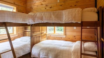 A cabin with a bunk bed arrangement, wooden walls, and a window providing natural light.