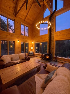 A cozy cabin interior with a fireplace, wooden furniture, and large windows. - The Grafton Lodge Secluded Green Mountain Escape (Grafton)