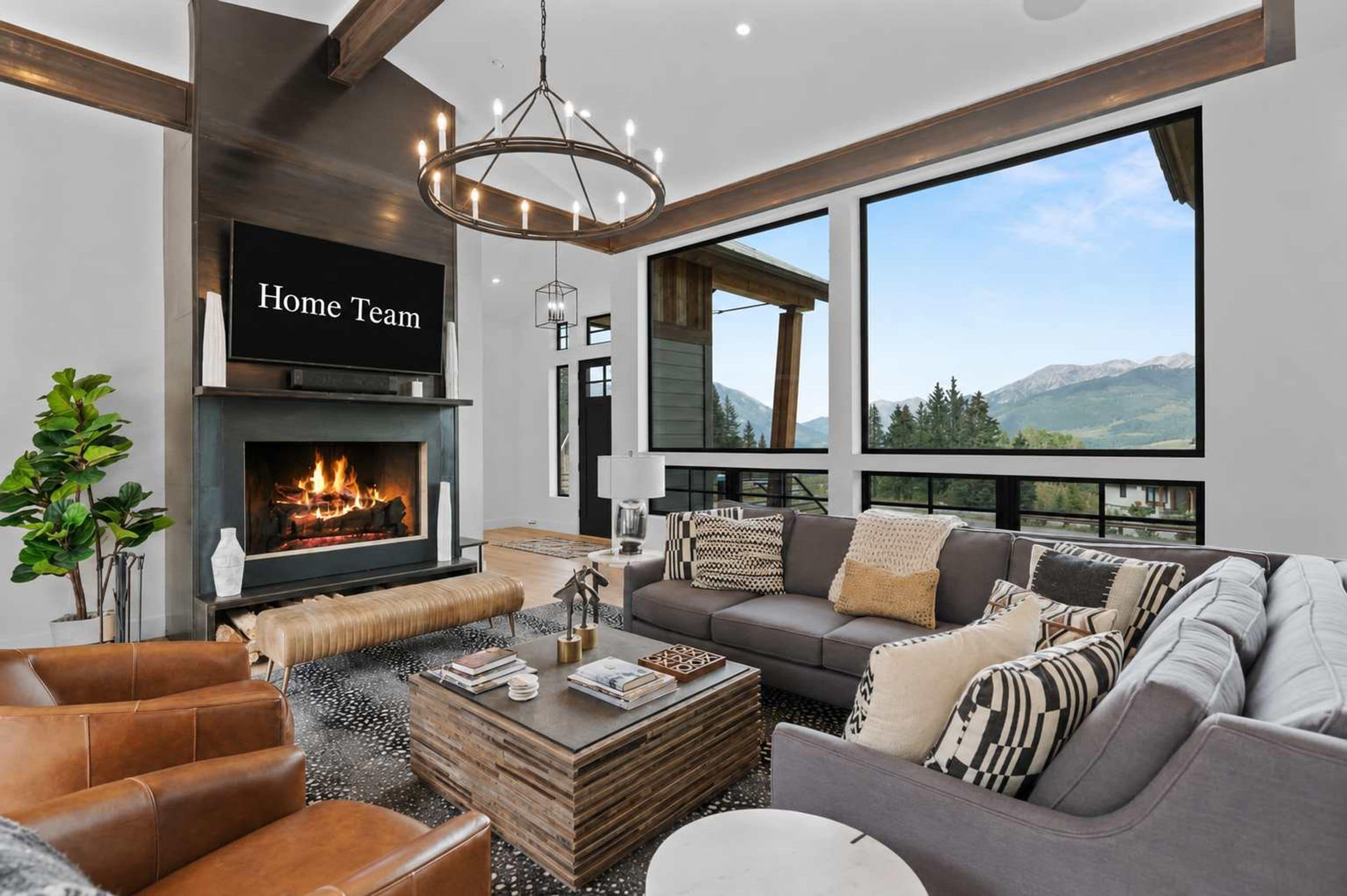 A modern living room with a fireplace, a large window with a mountain view, and a television labeled 'Home Team'.