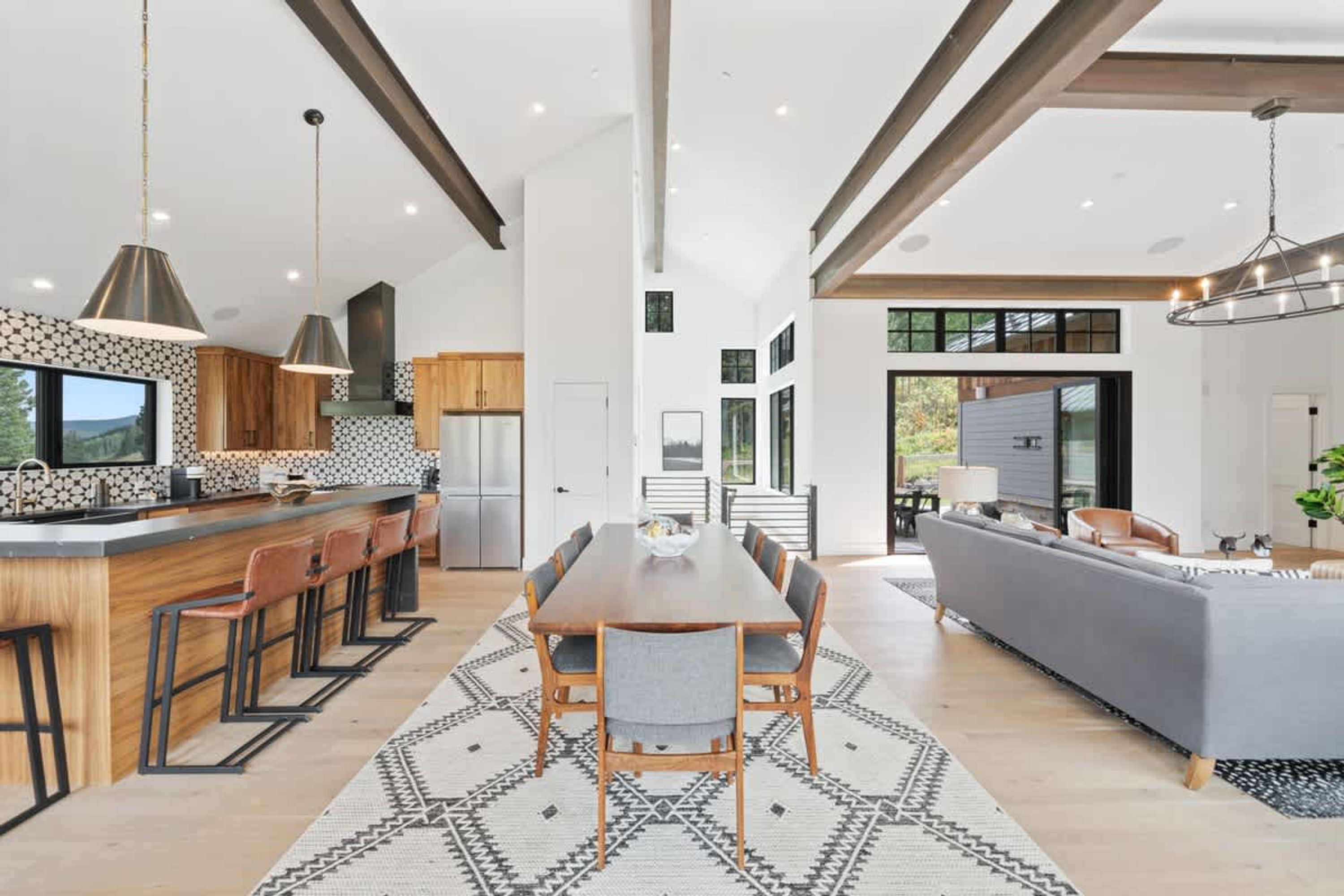 A modern kitchen with a central island, bar seating, and a dining area with a large table.