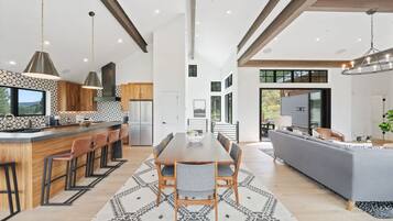 A modern kitchen with a central island, bar seating, and a dining area with a large table.