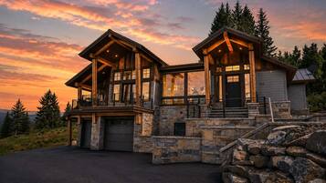 A two-story log cabin with a stone foundation and a garage.