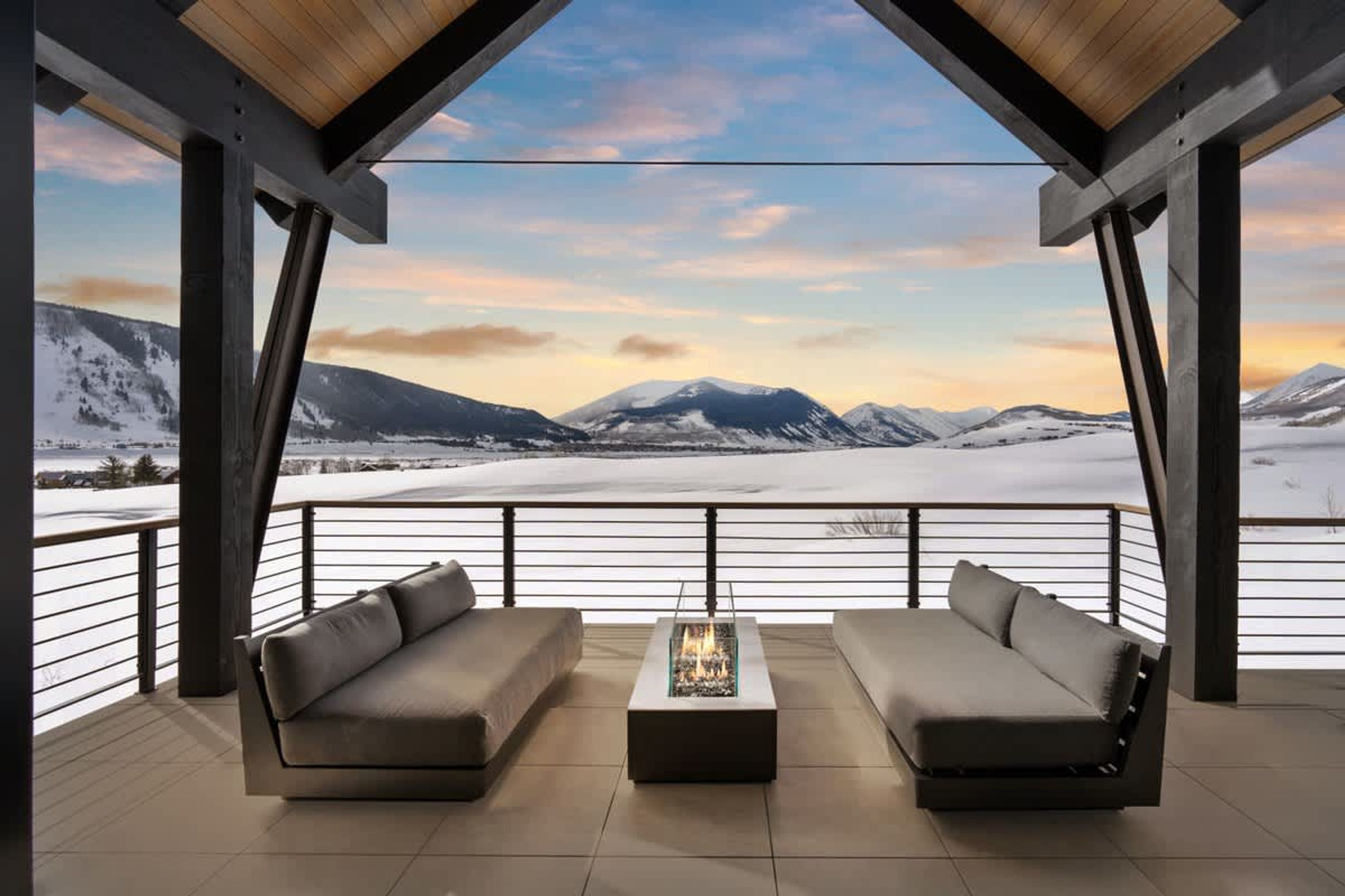 A balcony with a sofa and a table, overlooking a snowy mountain landscape.