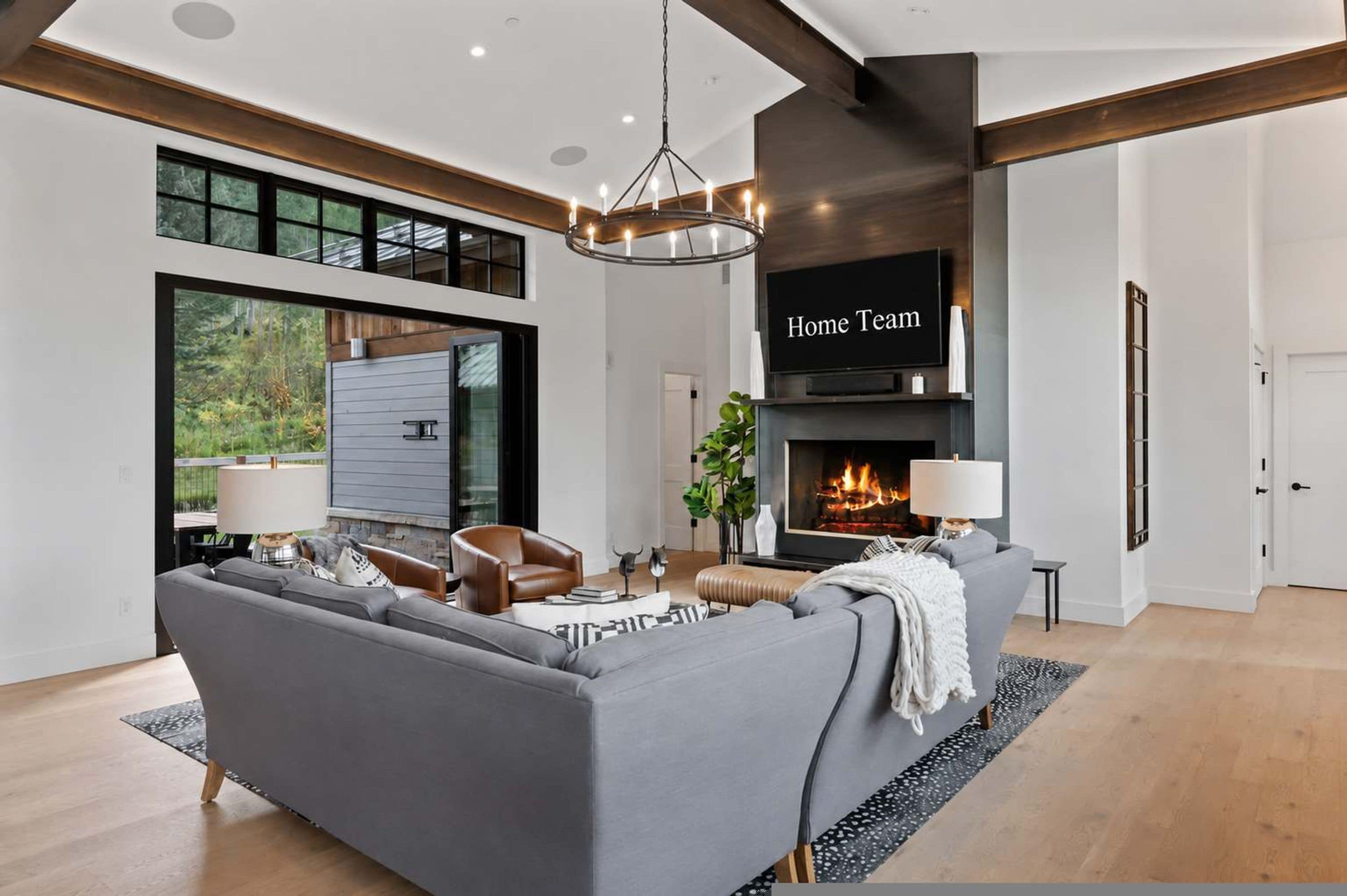 A modern living room with a grey sofa, a fireplace, and a large window.