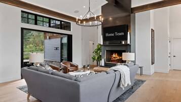 A modern living room with a grey sofa, a fireplace, and a large window.