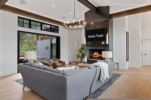 A modern living room with a grey sofa, a fireplace, and a large window. - Bear Scratch Mountain Views Modern Luxury (Crested Butte)