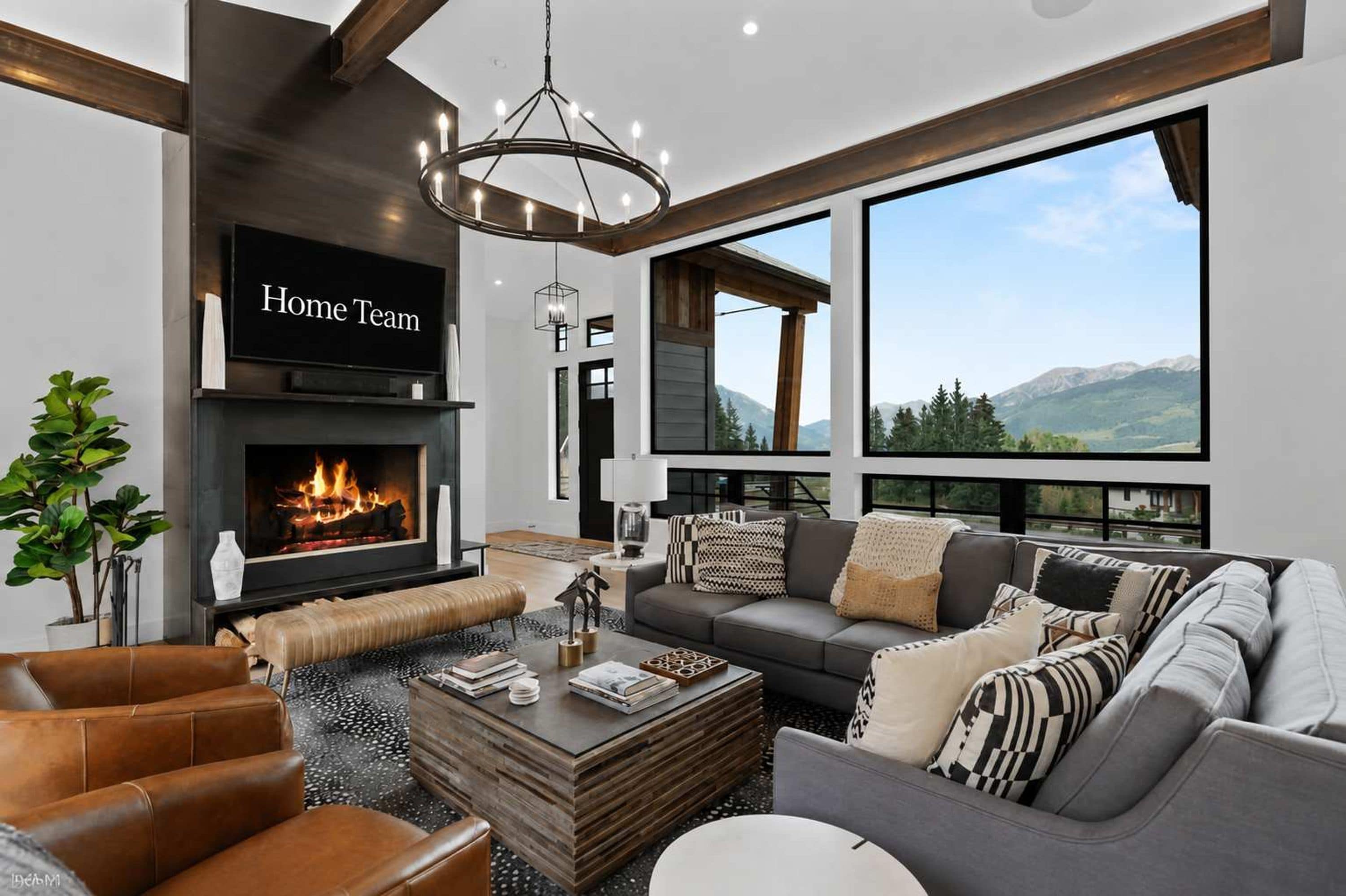 A modern living room with a fireplace, leather furniture, and a large window offering a mountain view.
