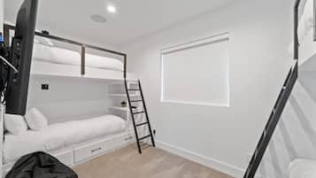 A bunk bed room with a ladder, a window, and a TV.