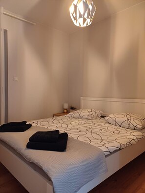 Een slaapkamer met een bed, een nachtkastje met een lamp en een hanglamp.