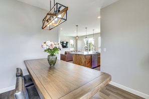 A dining area with a wooden table, a vase with flowers, and a modern pendant light.