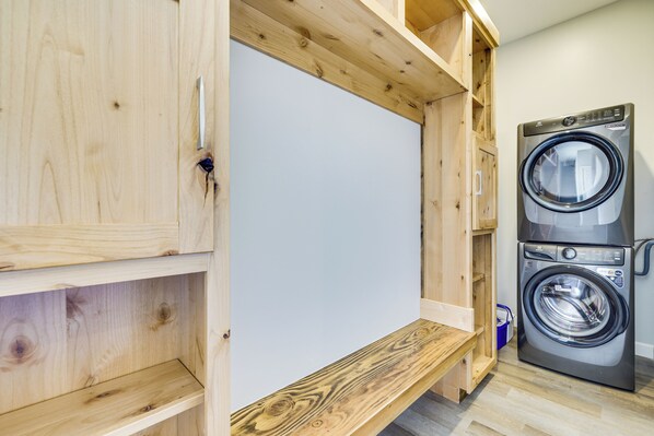 A laundry room with wooden cabinets and a stacked washer and dryer.